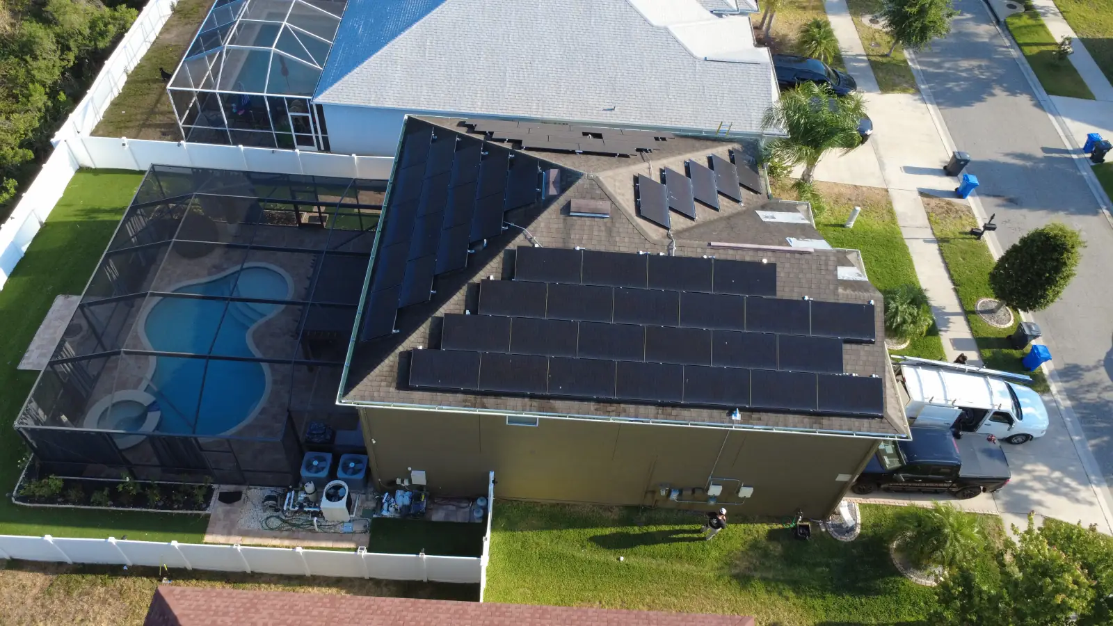 Aerial view of a completed residential solar installation on a Florida home with a pool and a work truck in the driveway